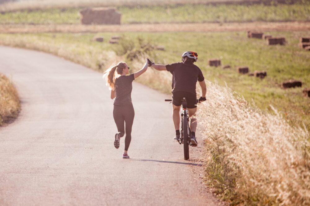 Woman running next to man on bicycle